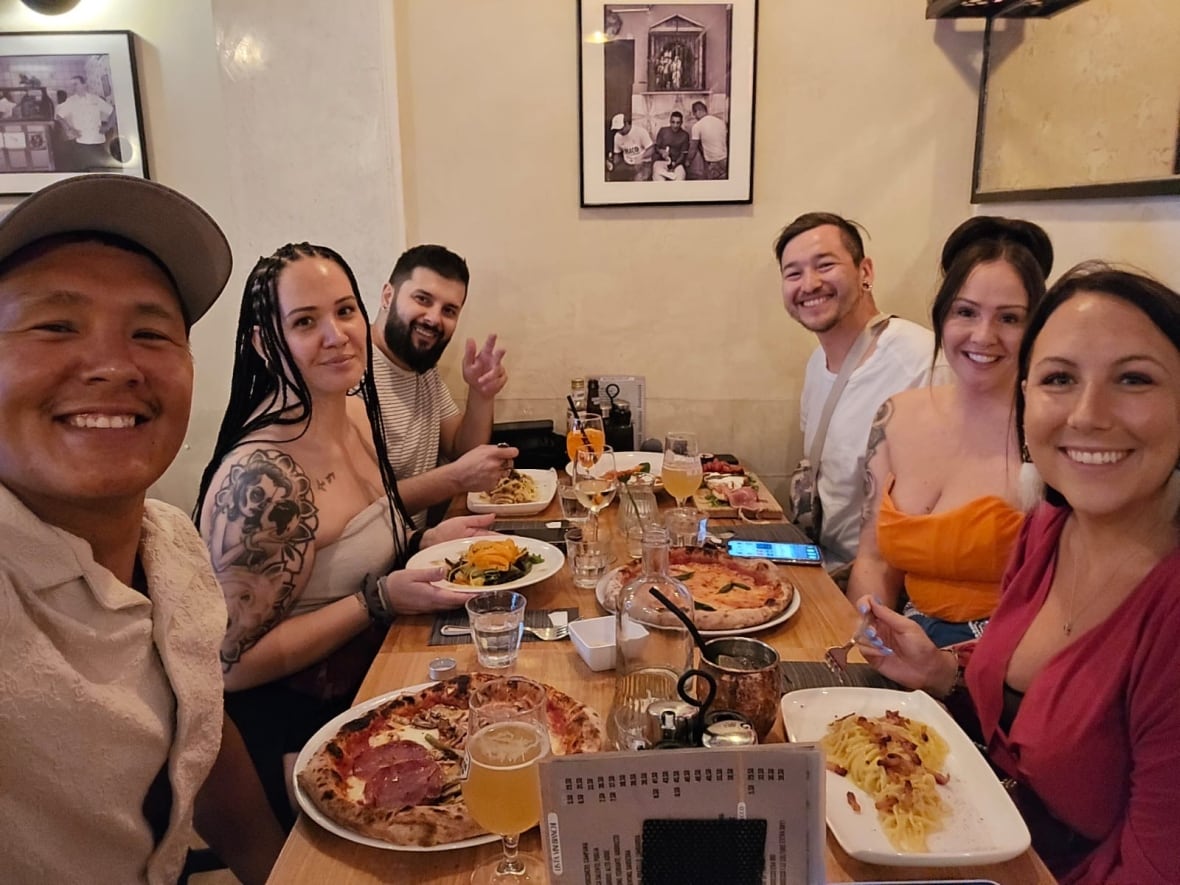 Six people smile around a dinner table.