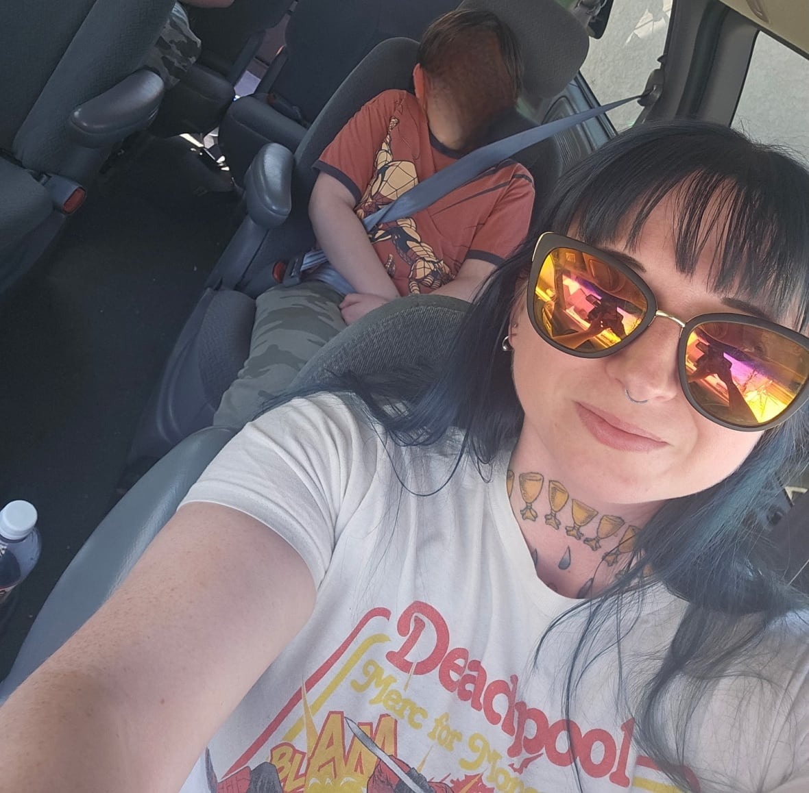 A woman and two children are sitting on a car.