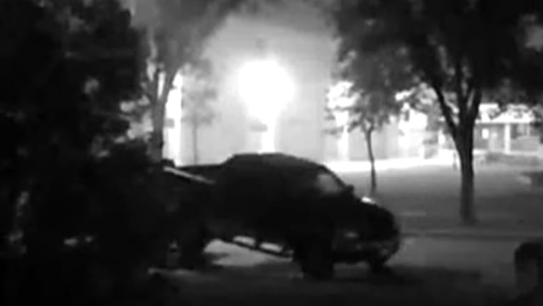 A truck is being pulled by a tow truck on a black and white image. 