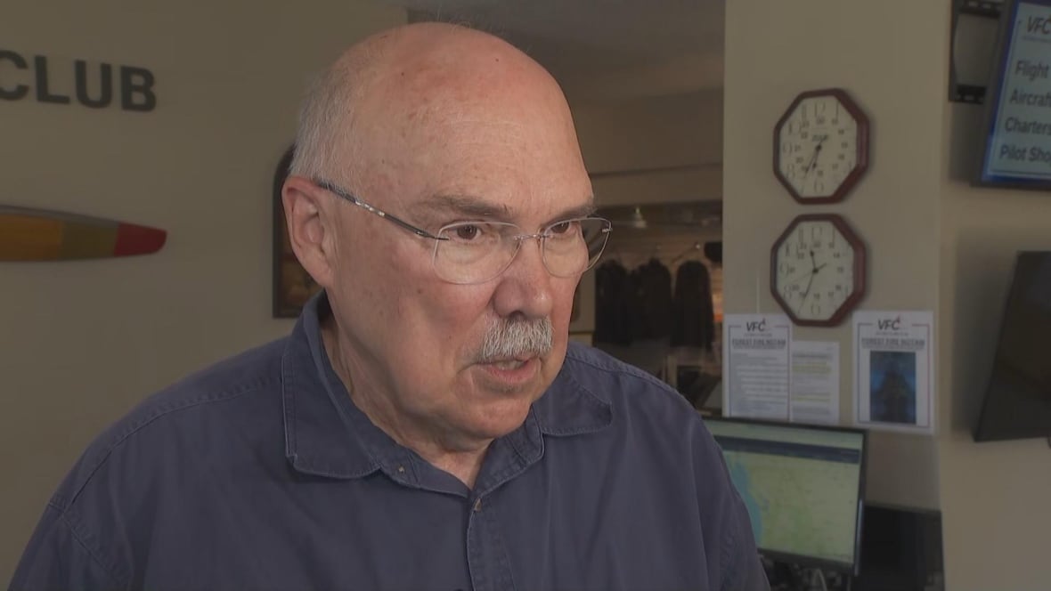 A bald man is seen speaking in an office environment.