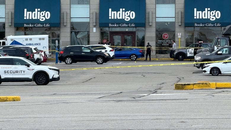 Police tape surrounds a crime scene in a parking lot of a bookstore.