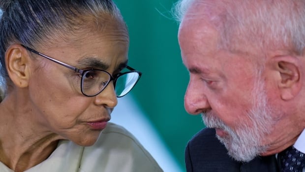 An older woman and an older man lean in toward each other to speak