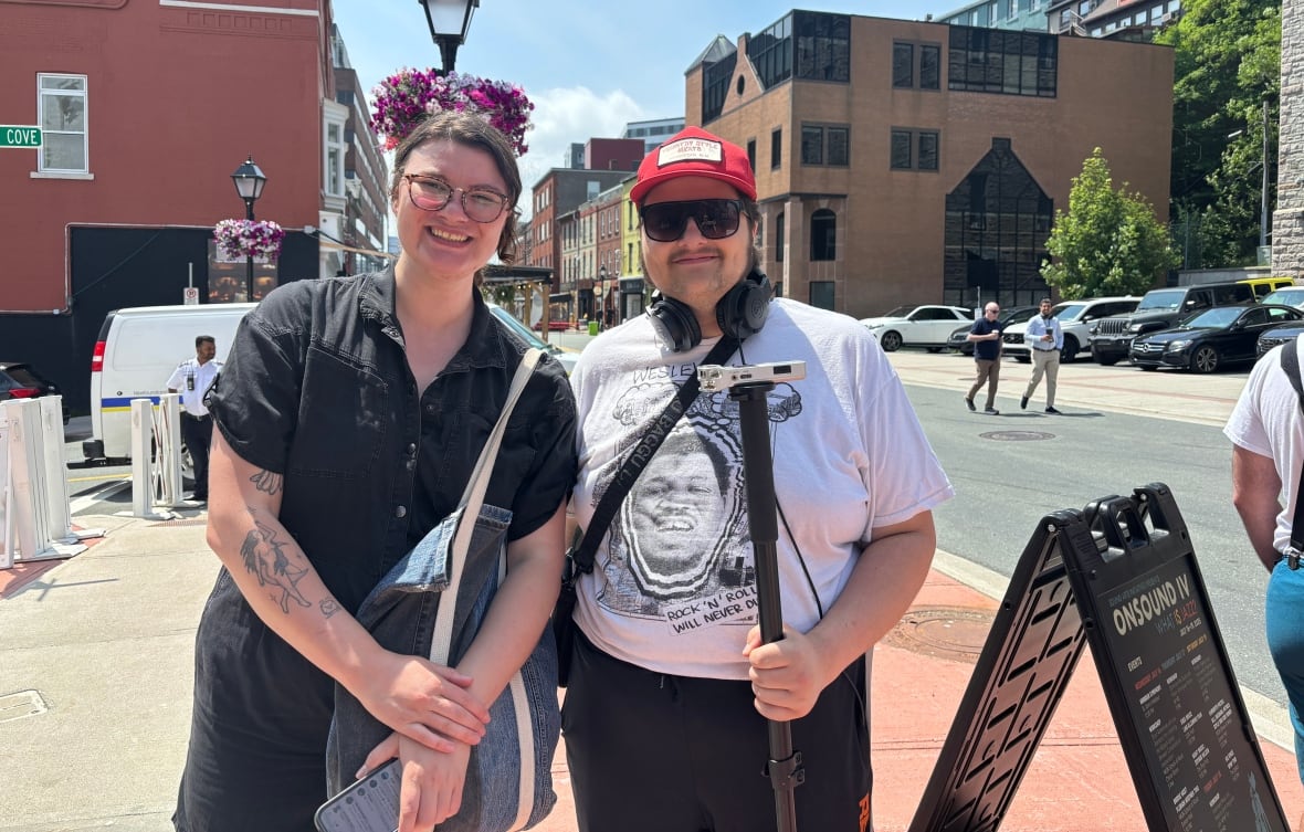 Two people stand side by side on a busy sidewalk.