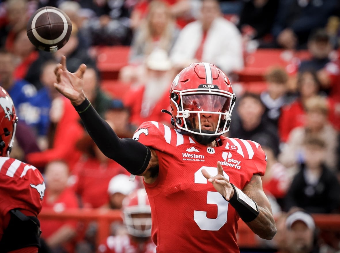 A football quarterback in red uniform throws the ball