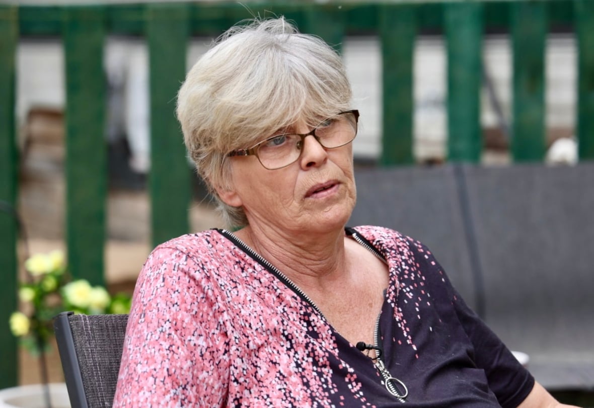 A woman with glasses and short hair speaks to a reporter. 