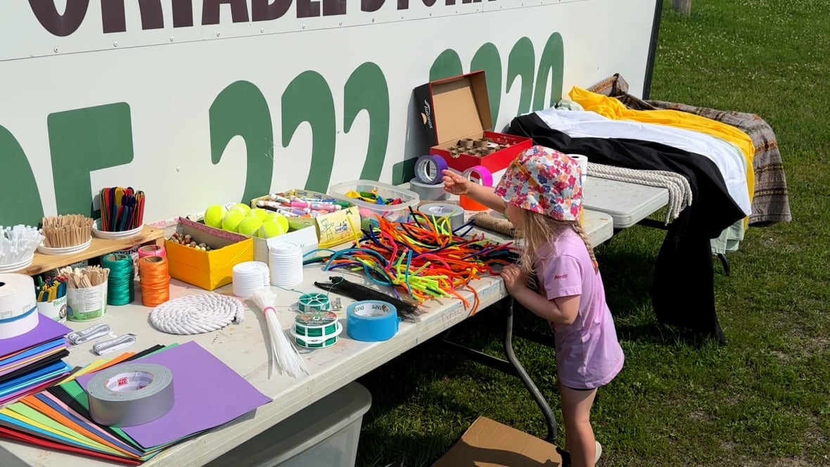 A child leaning over a table and grabbing some items.
