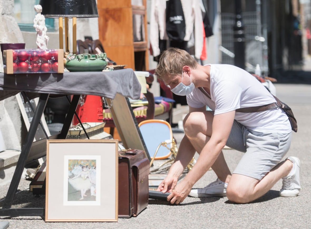 A man leans down to look at garage sale items