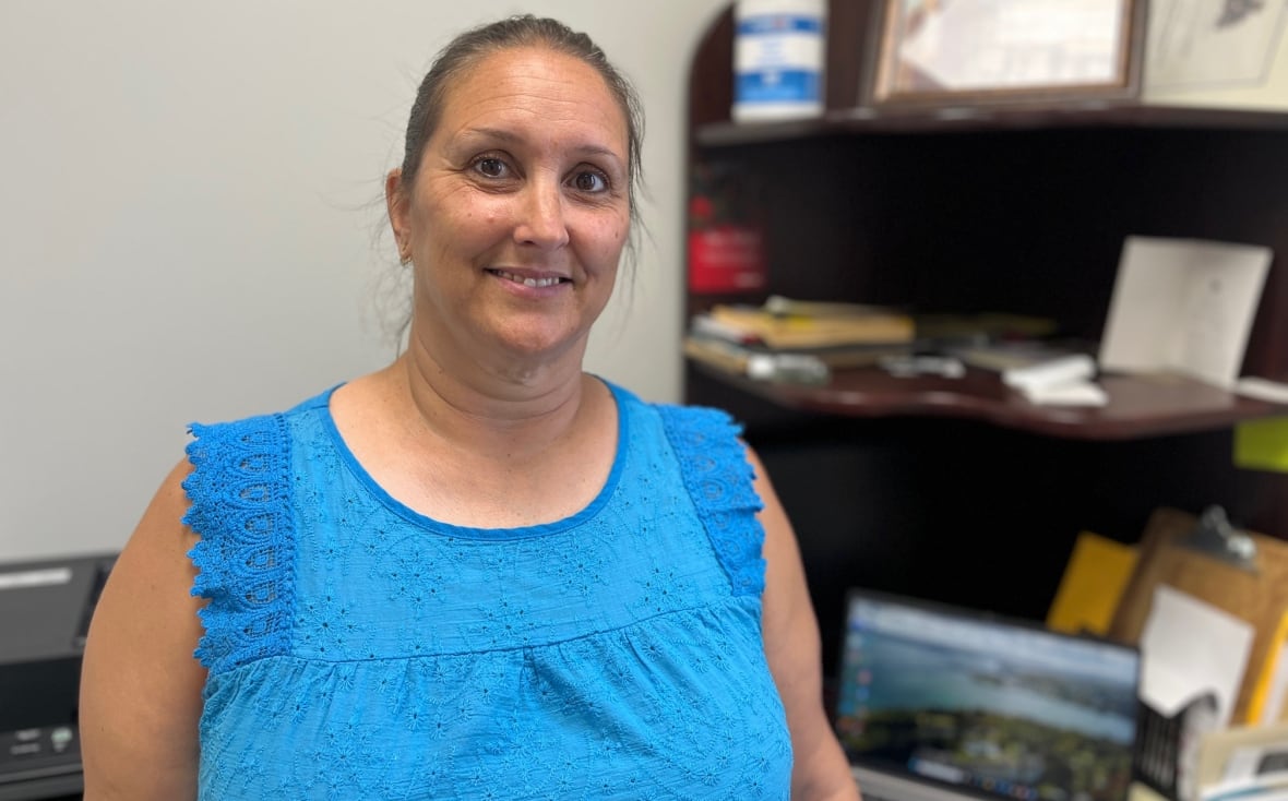A woman in a blue shift poses for a portrait.