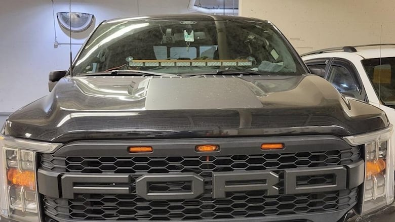 A black Ford F-150 with a light bar in the lower centre of the windshield.