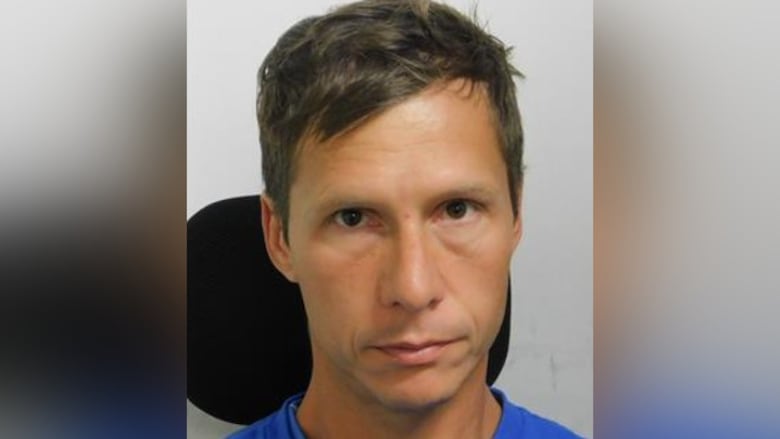 A man with a blue T-shirt looks at the camera.