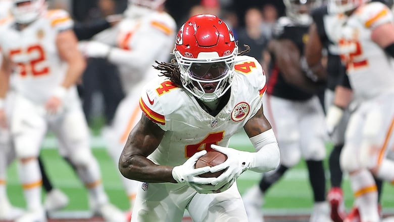 A men's football player runs with the ball during a game.