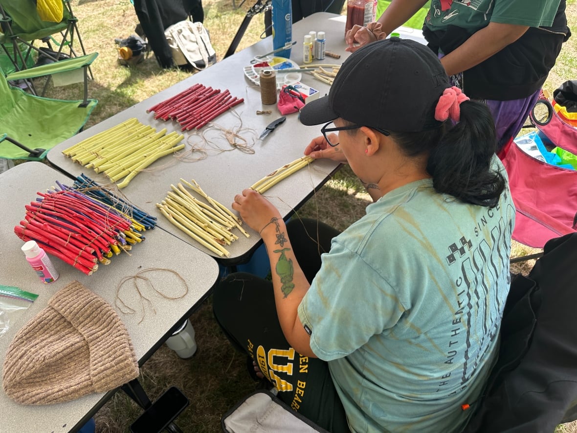 A person sitting at a table with small items of different colours.
