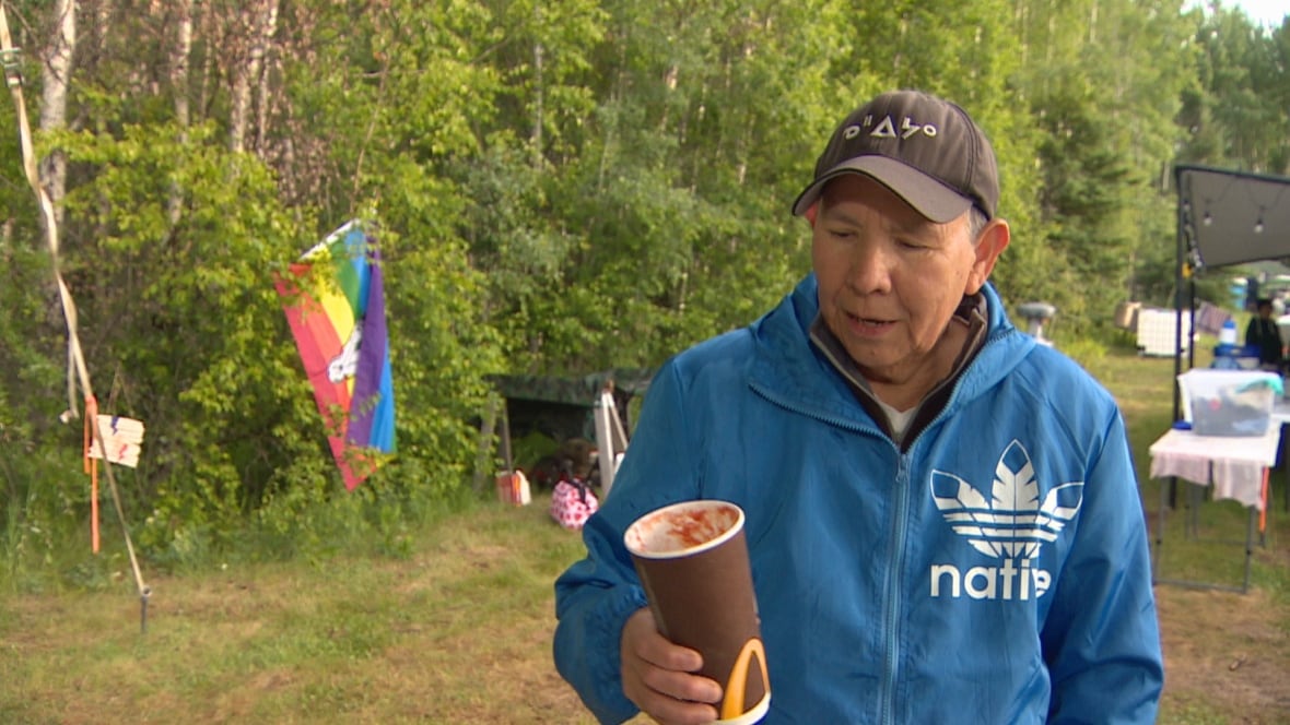 A person in blue hold a coffee cup with tomato juice in it.