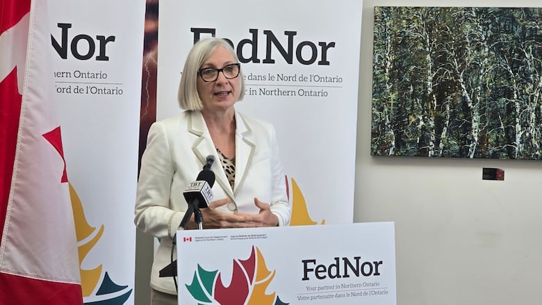 A woman speaks at a podium surrounded by FedNor signs.