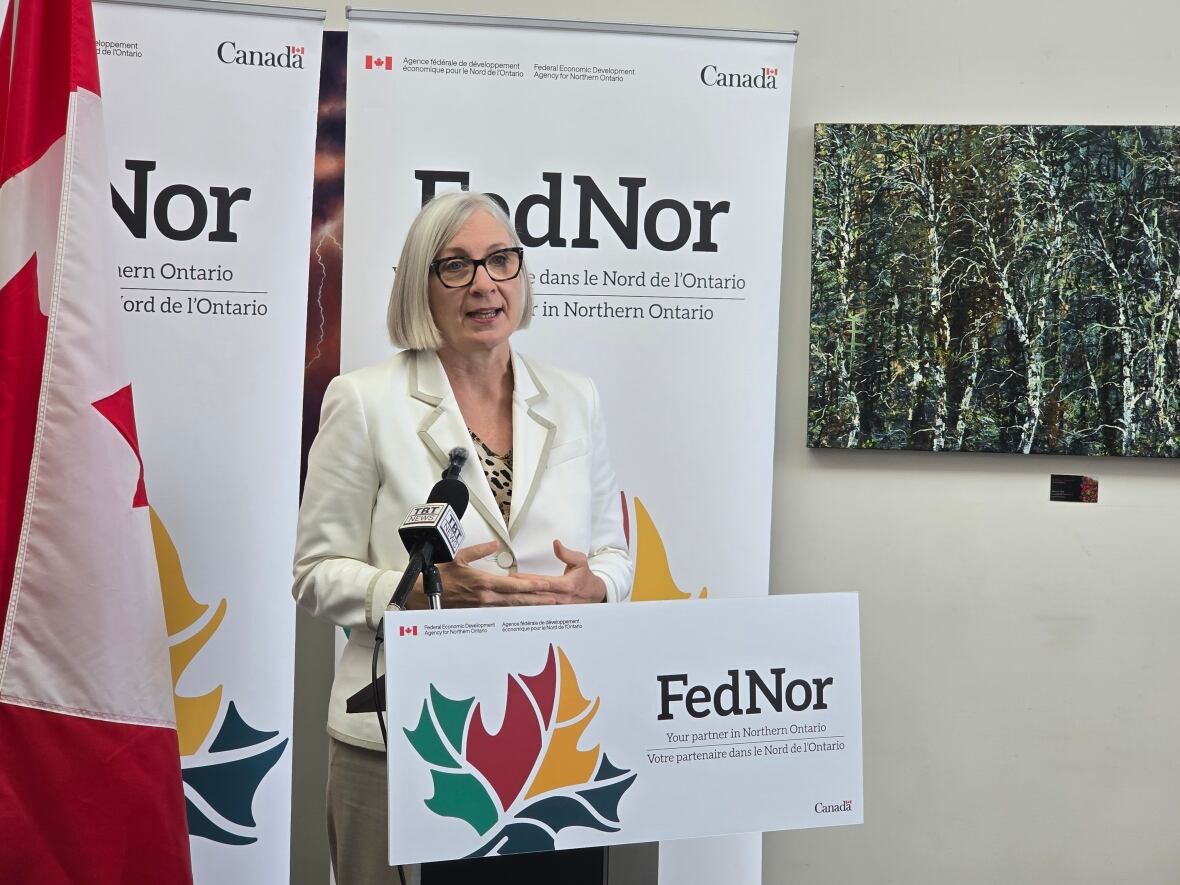 A woman speaks at a podium surrounded by FedNor signs.