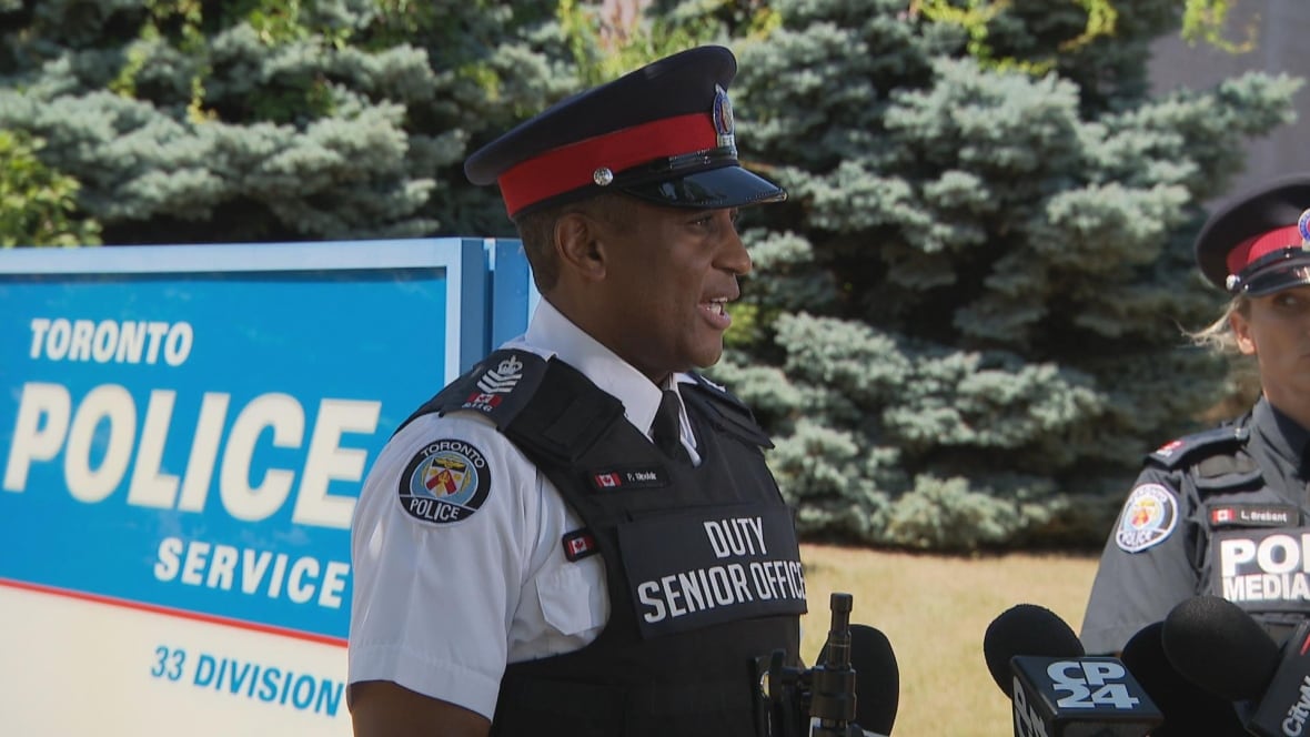 Cop in uniform stands in front of Toronto Police 33 Division sign speaking with reporters