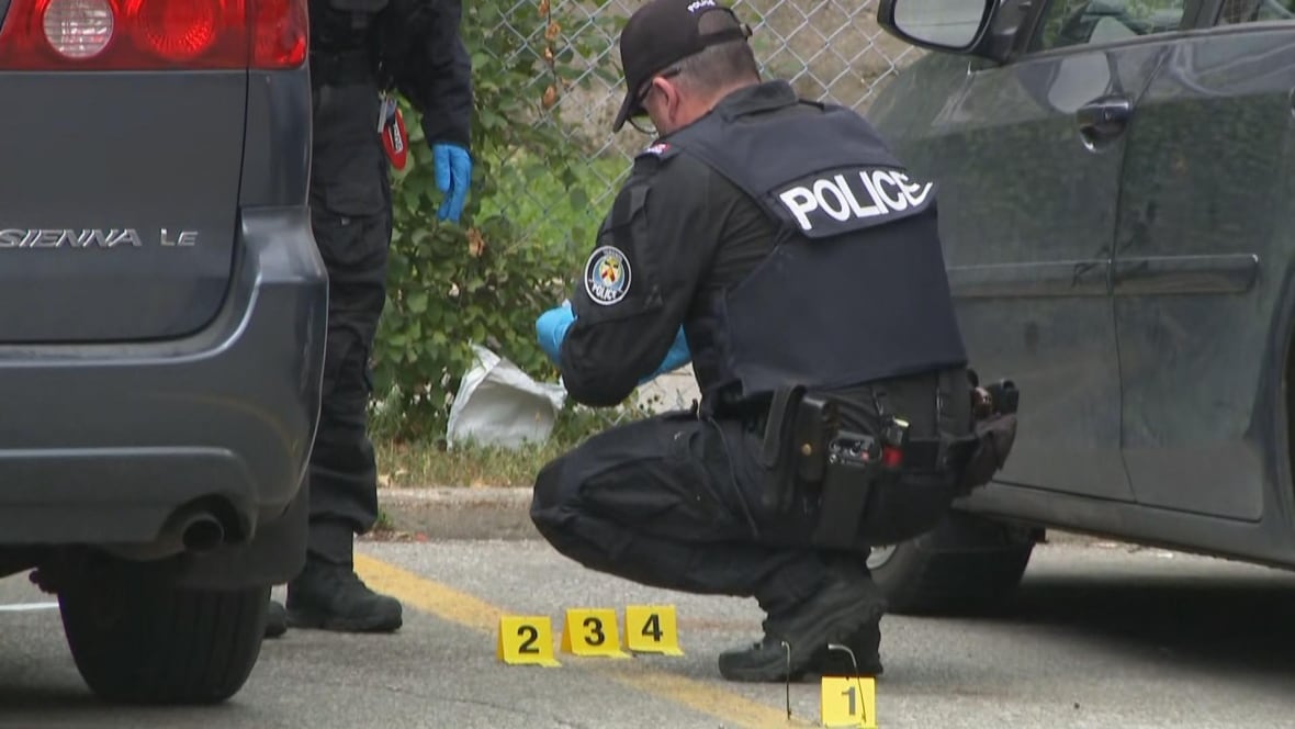 Two officers in uniform with evidence markers on the ground in the middle of two cars