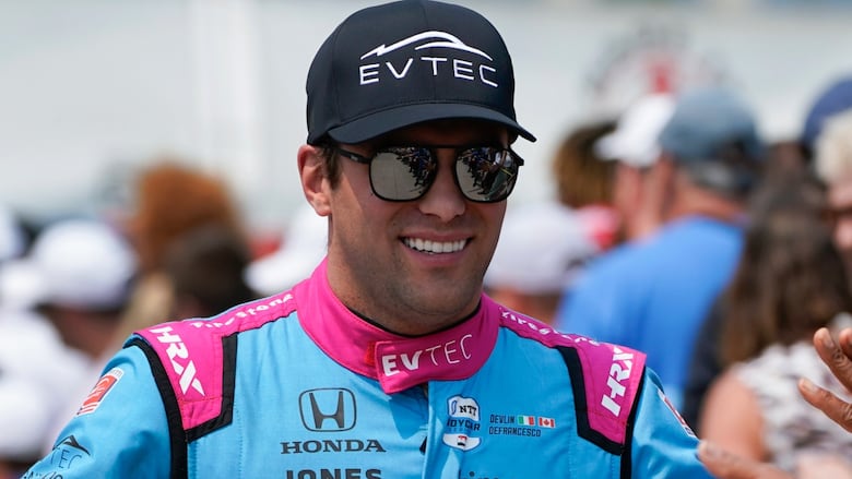 racing driver, wearing sunglasses and hat, smiling
