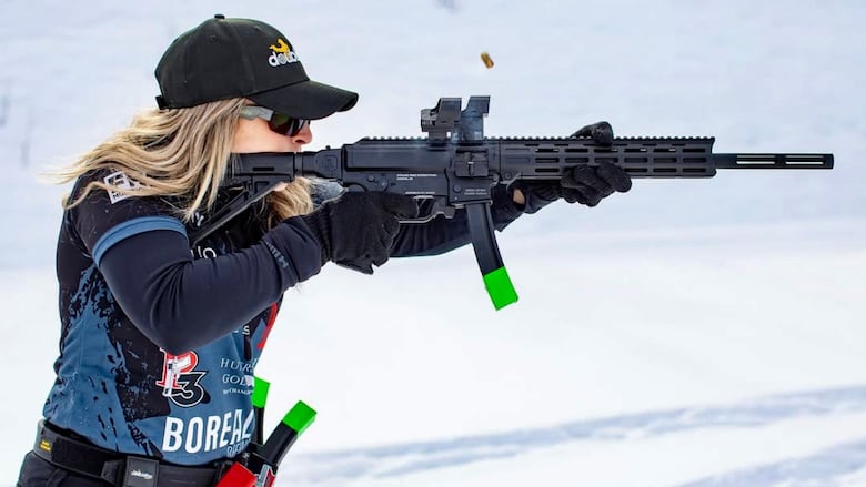 A woman holds a gun, surrounded by snow.