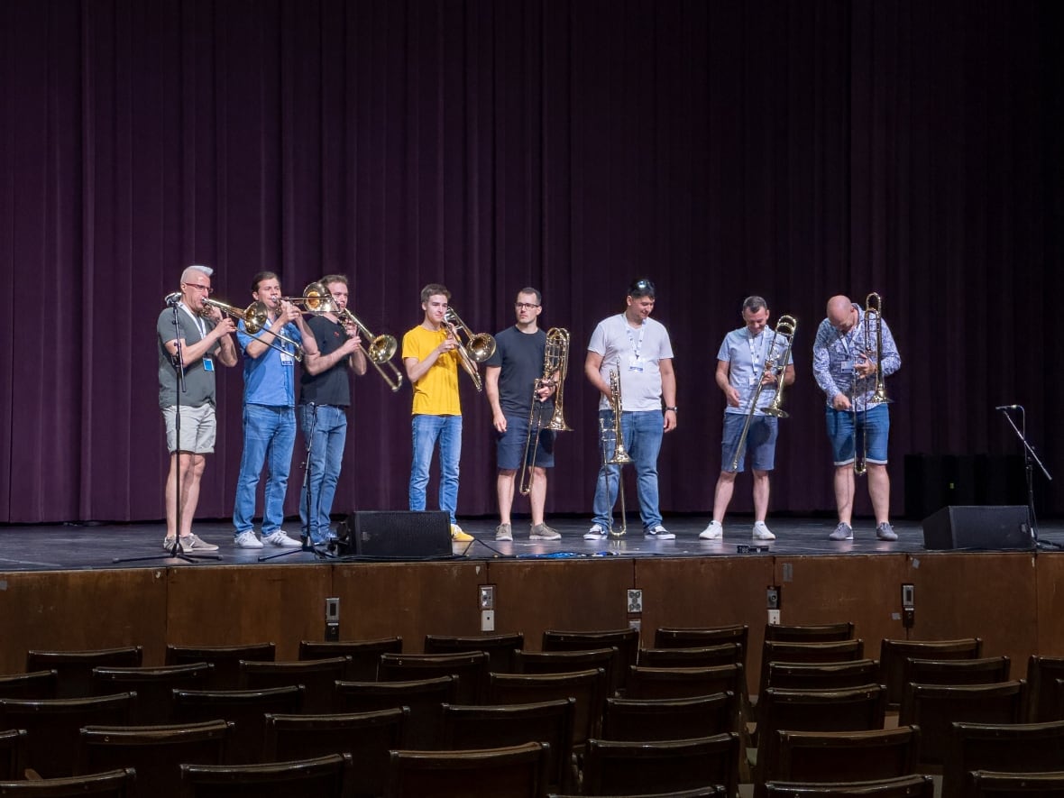 A small group of people on stage with trombones