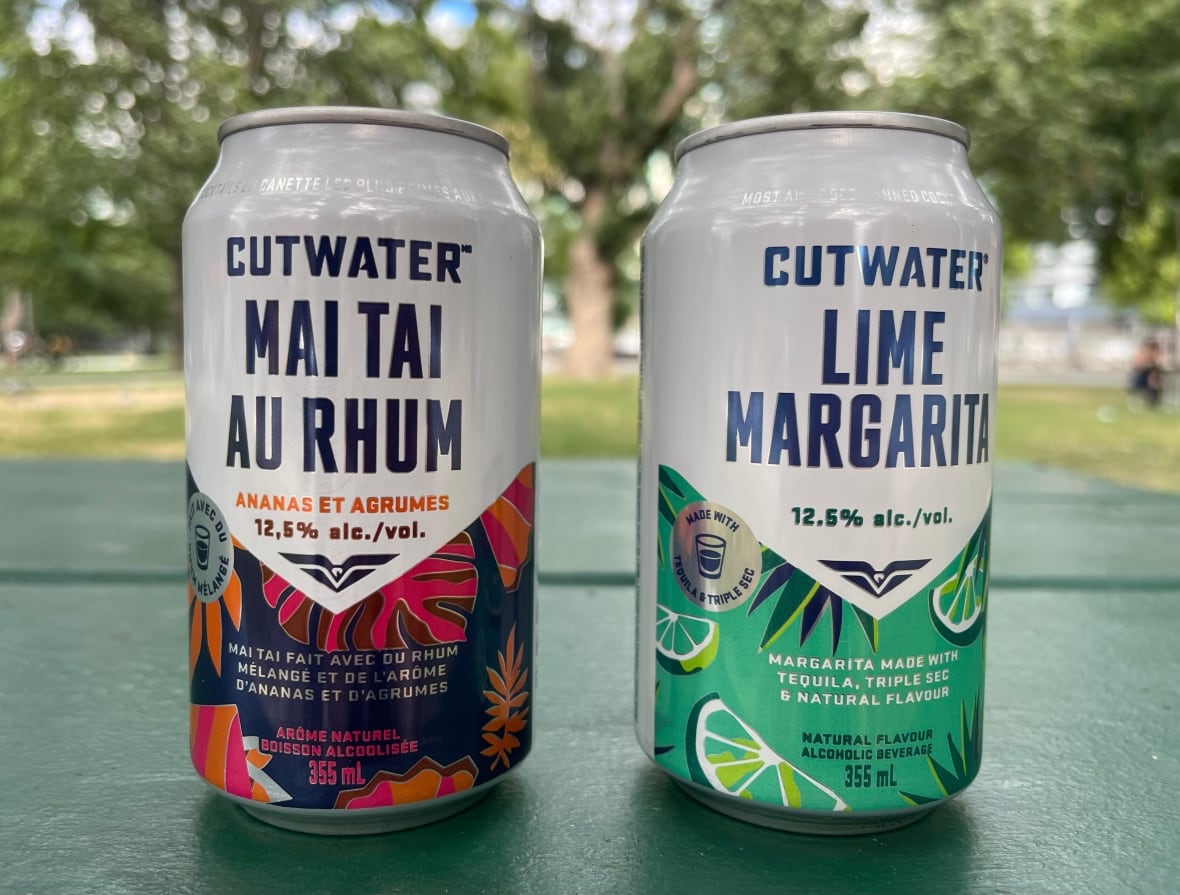 two cans with fruit-centric designs sit next to eachother on a park bench.