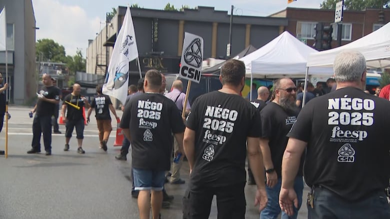 A group of people, mostly men, wearing black shirts with the words "Négo 2025" on the back 