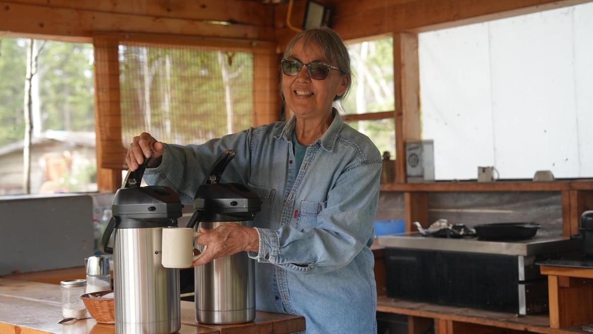A woman fills a cup from a carafe.
