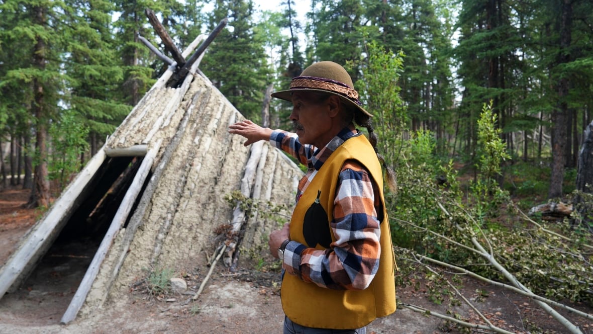 A man in front of a wooden structure.