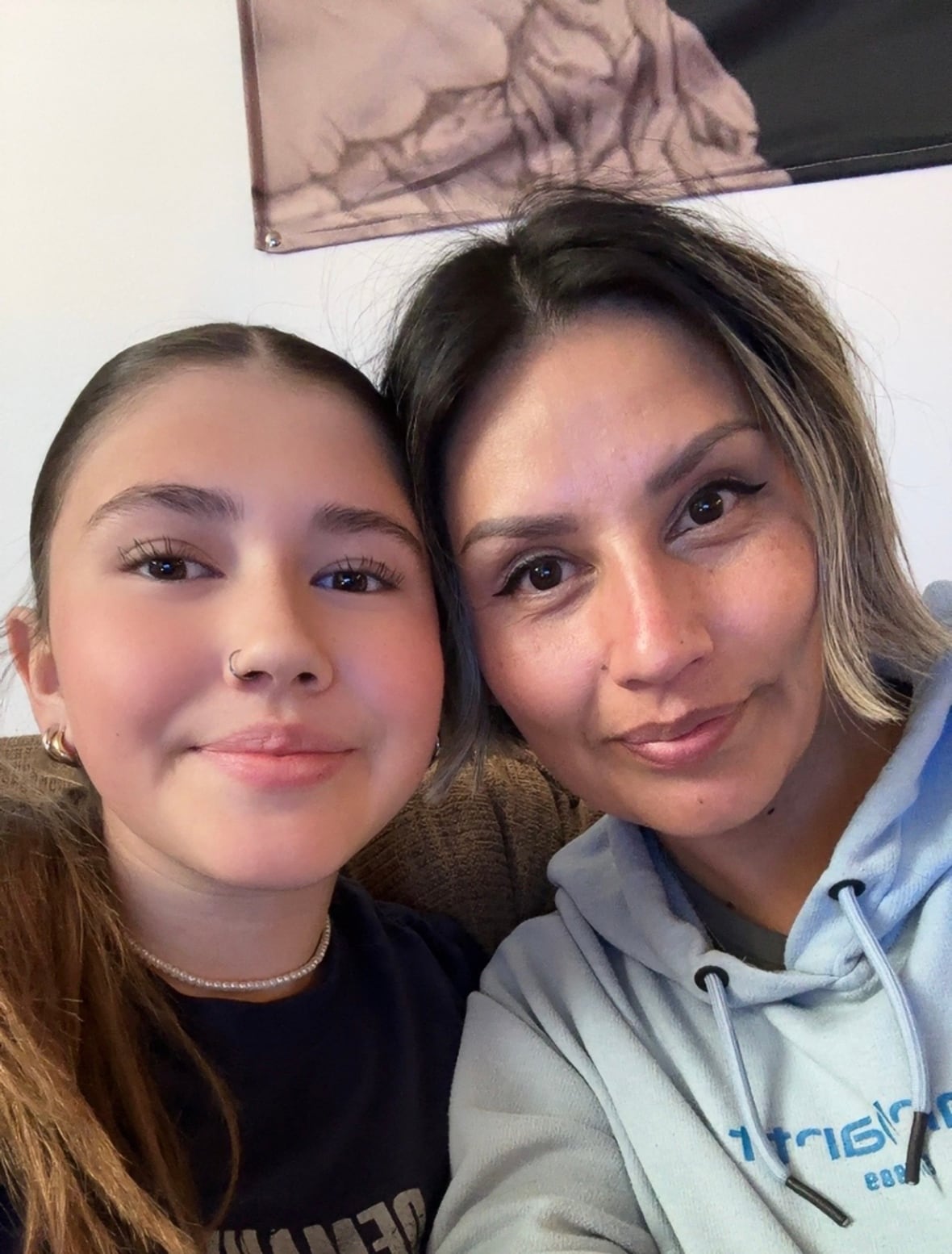 A woman and a teenage girl smile and pose for a selfie.  