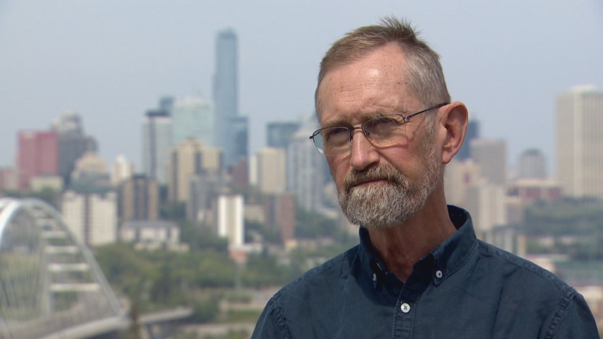A man with glasses and a grey bird stands in Edmonton's river valley.