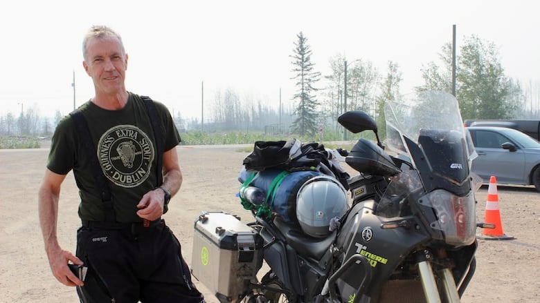 A man standing next to a motorcycle.
