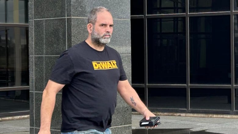 A man in a black tshirt exiting a courthouse.