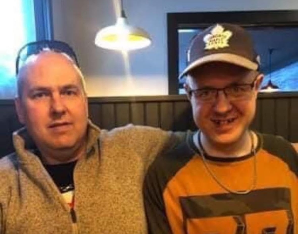 Two men sit at a booth table smiling. 