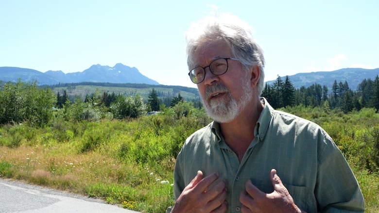 Dave Weaver stands in front of Mount Arrowsmith, with a visible clearcut in the foothills. 