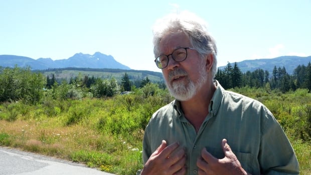 Dave Weaver stands in front of Mount Arrowsmith, with a visible clearcut in the foothills. 
