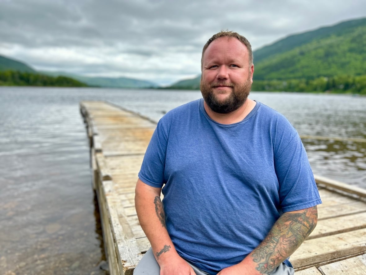 Man in blue t-shirt sitting on a wharf.