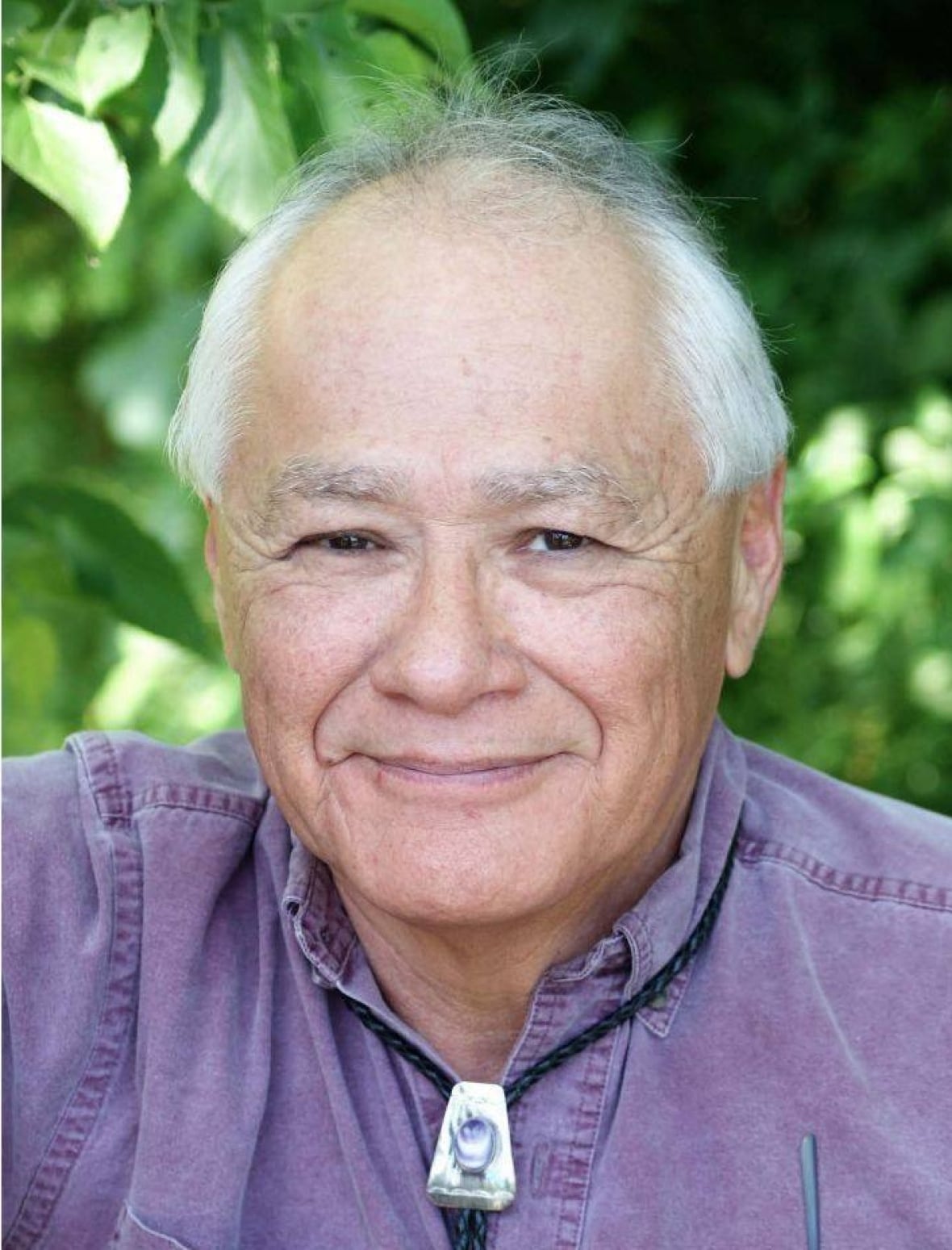Head shot of a man smiling in a purple shirt.