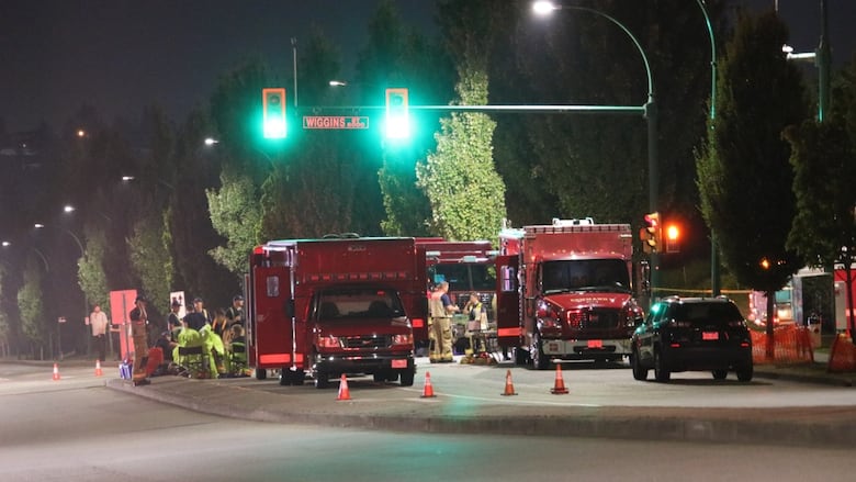 Red emergency vehicles parked on a street at night. 