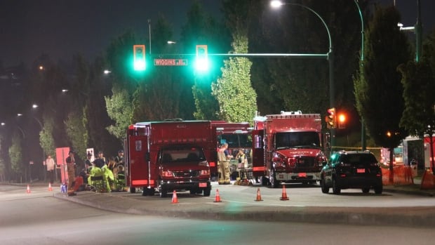 Red emergency vehicles parked on a street at night.