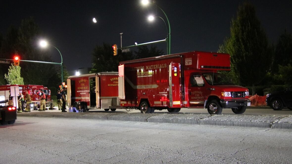 Red emergency vehicles parked on a street at night. 