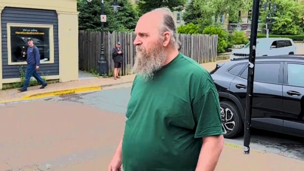 A man with a beard and a green T-shirt is shown.