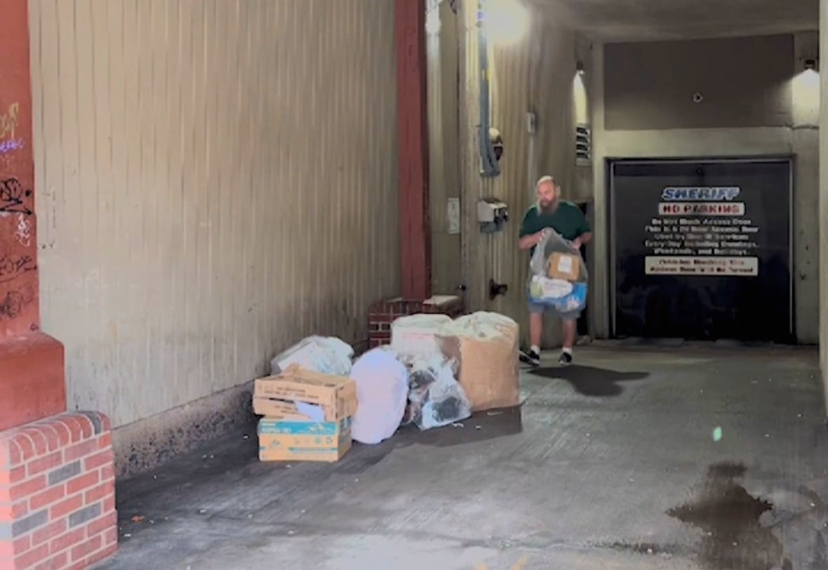 A man is shown holding a plastic bag in a loader bay.