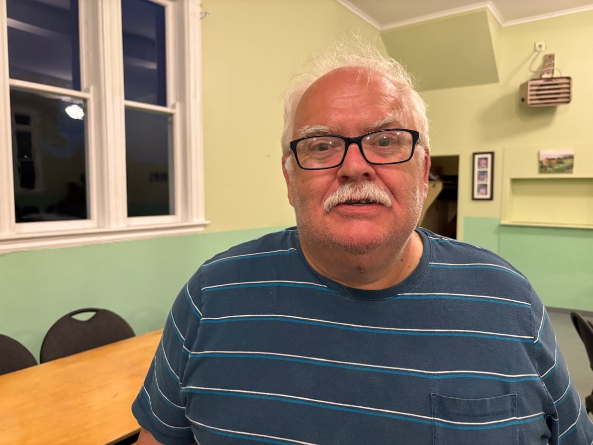 A man wears glasses and a striped shirt.
