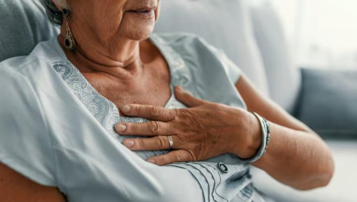 woman holding her chest with her hand as if she is experiencing chest pain