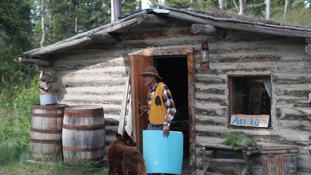 A man stepping out of an old cabin.
