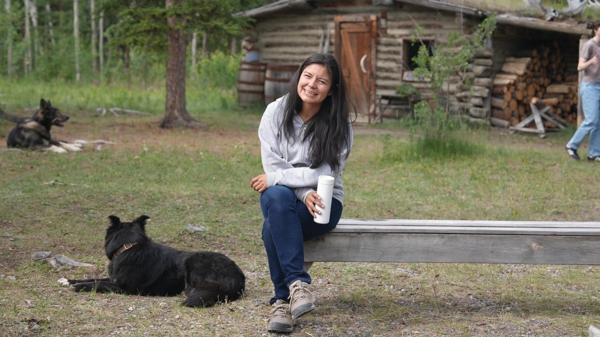 A portrait of a woman sitting on a bench, smiling at the camera.