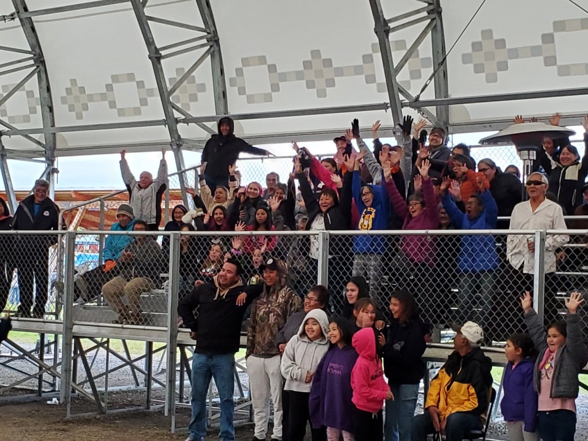 A photo of a crowd in metal bleachers under a big tent canopy.