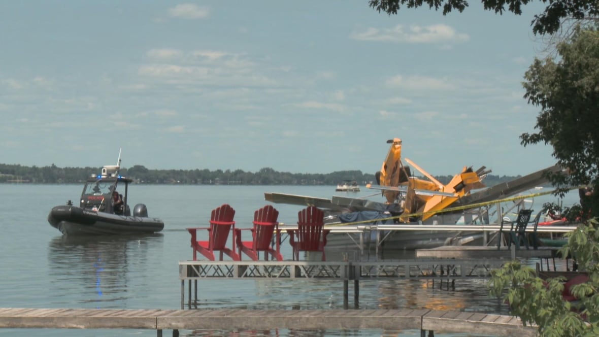 A police boat is near a crashed yellow seaplane.