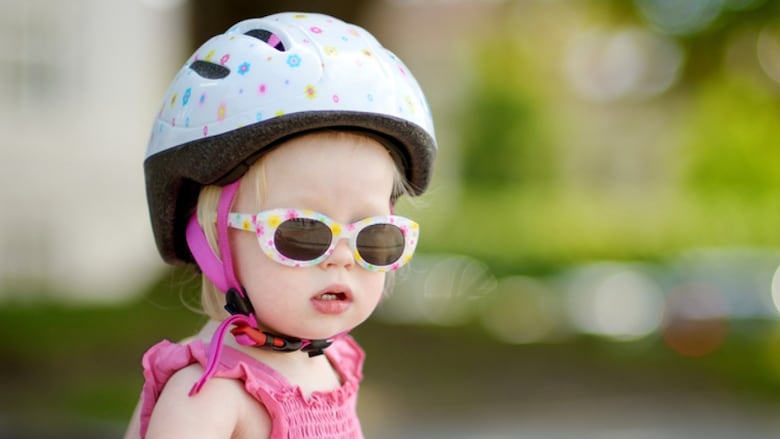 Little toddler girl wearing sunglasses and a bicycle helmet
