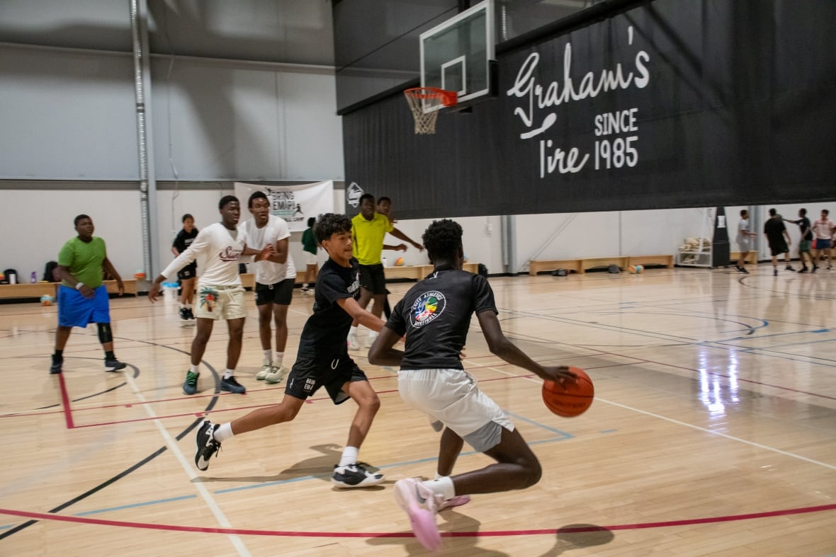 A group of kids play basketball in an indoor court.